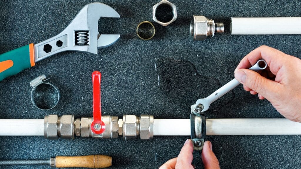 Plumber repairing a pipe valve with an adjustable wrench in Panama City