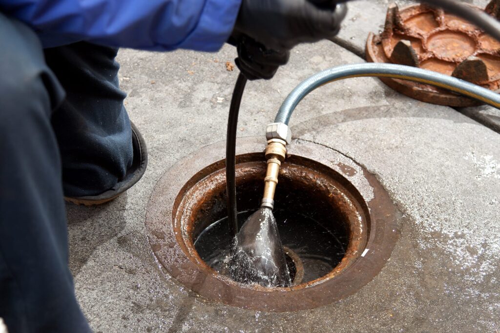 Plumber hydro jetting a sewer line through a manhole in Panama City