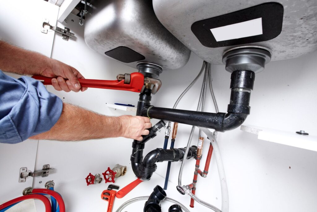 Plumber repairing drain pipes beneath a kitchen sink in Panama City