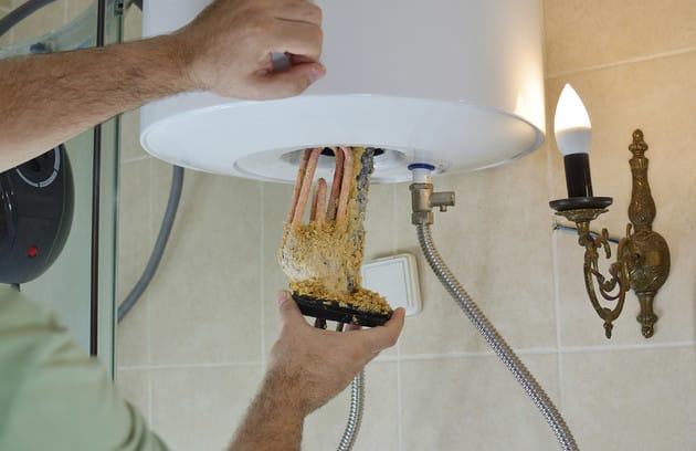 Technician removing mineral buildup from a water heater in Panama City